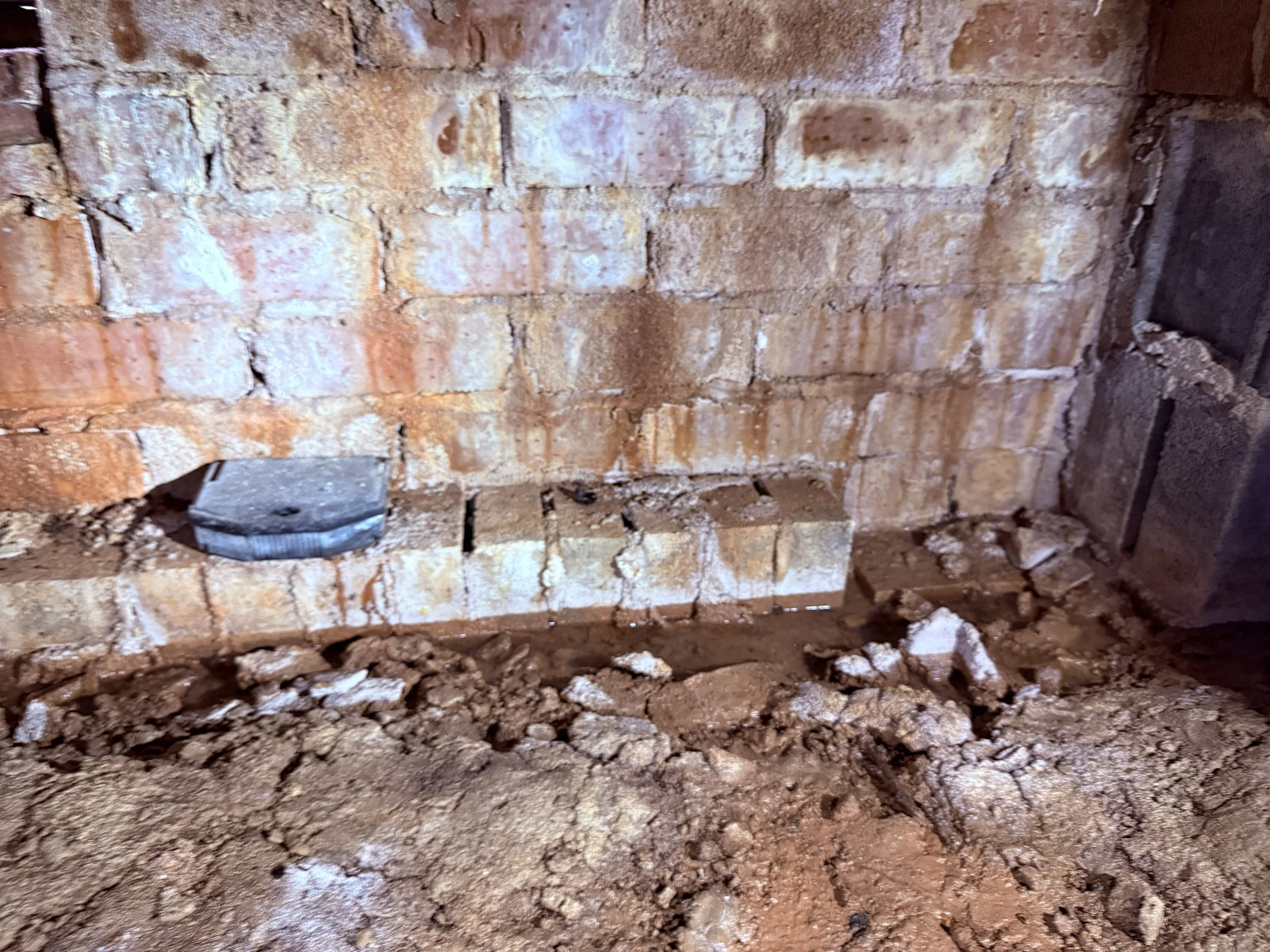 Rainwater intrusion entering a crawl space through the foundation wall and creating standing water, damp soil and moisture problems beneath the home