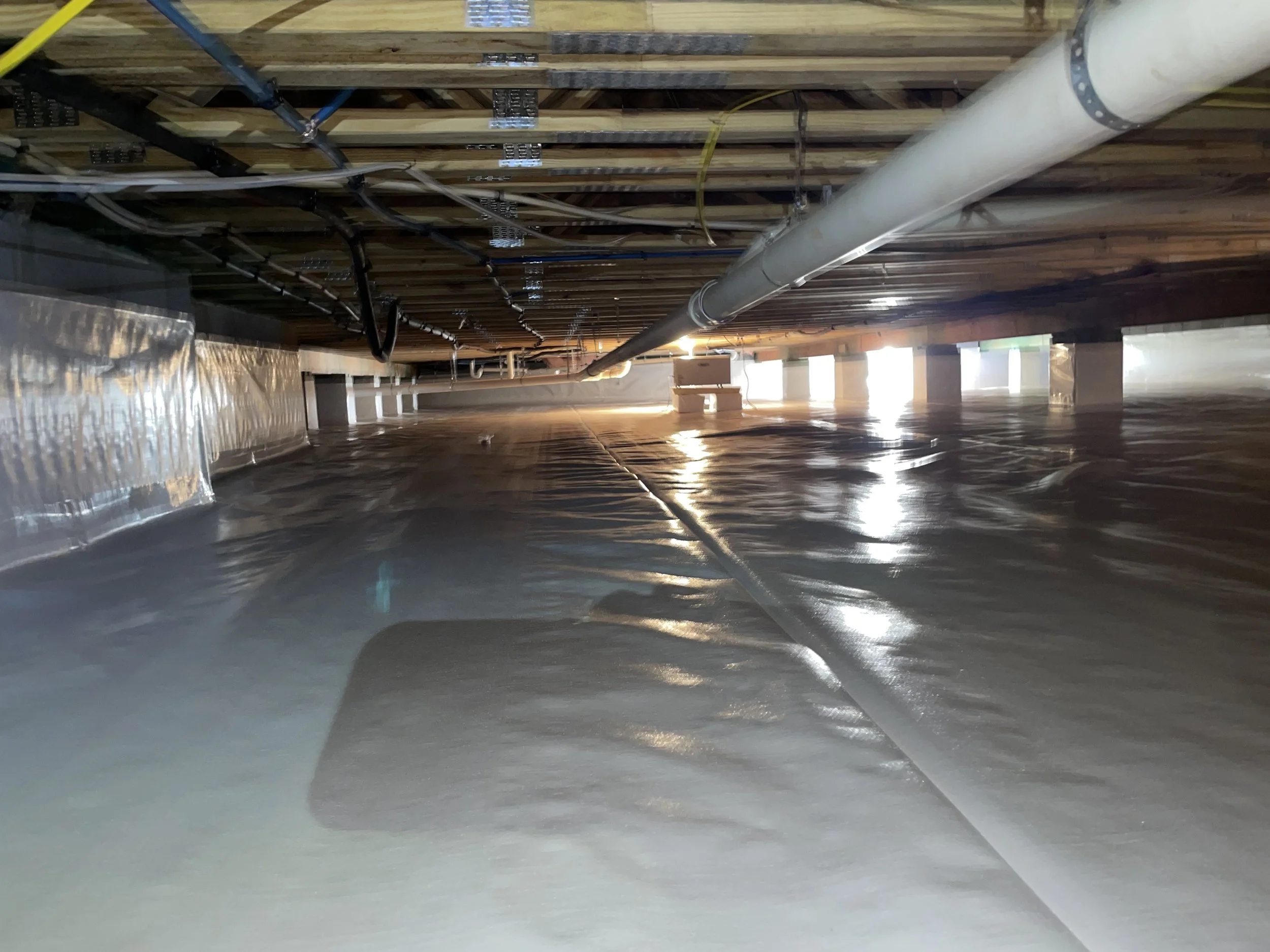 Encapsulated crawl space with sealed liner, wrapped piers and a crawl space dehumidifier installed beneath the home