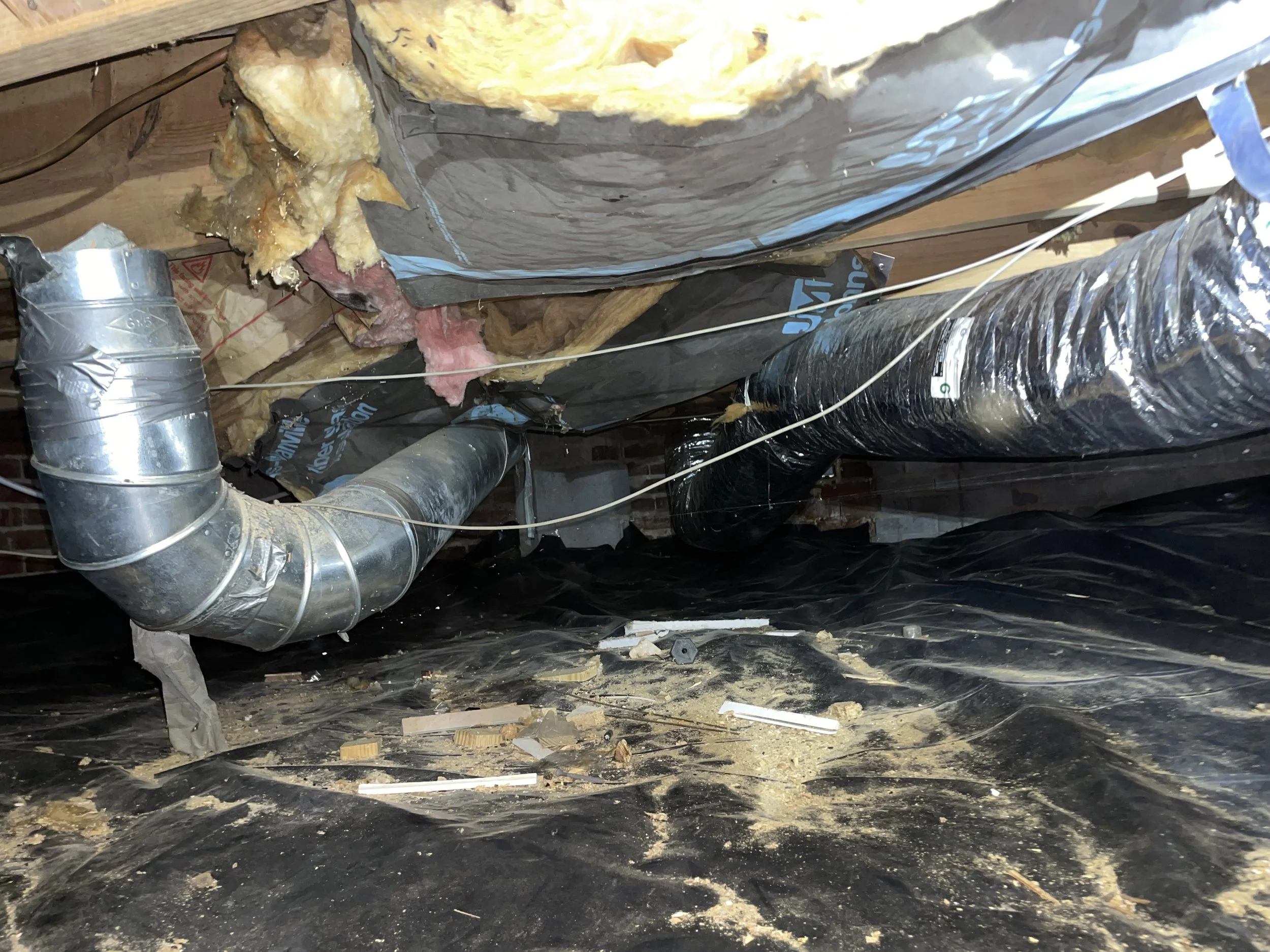 Statesville crawl space with fallen insulation, damaged vapor barrier, debris and exposed HVAC ductwork