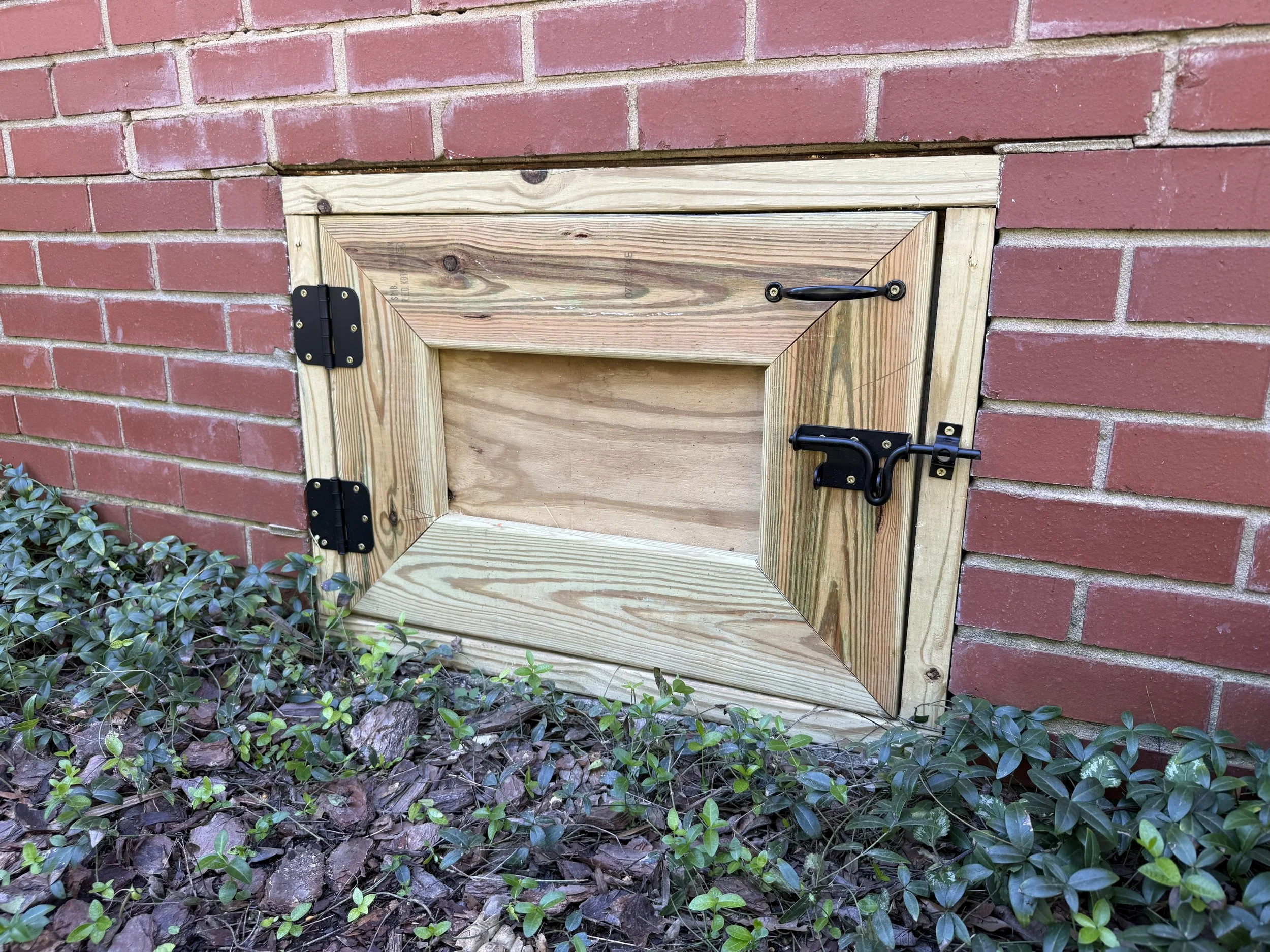 New wood crawl space access door with secure hinges and latch, replacing the rotted door and broken hardware at a Charlotte-area home.
