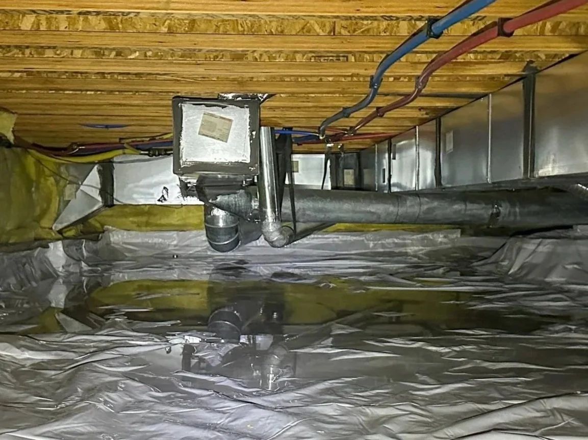 Encapsulated crawl space with condensation and standing water on top of the vapor barrier near HVAC ductwork, showing the need for dehumidification and water control.