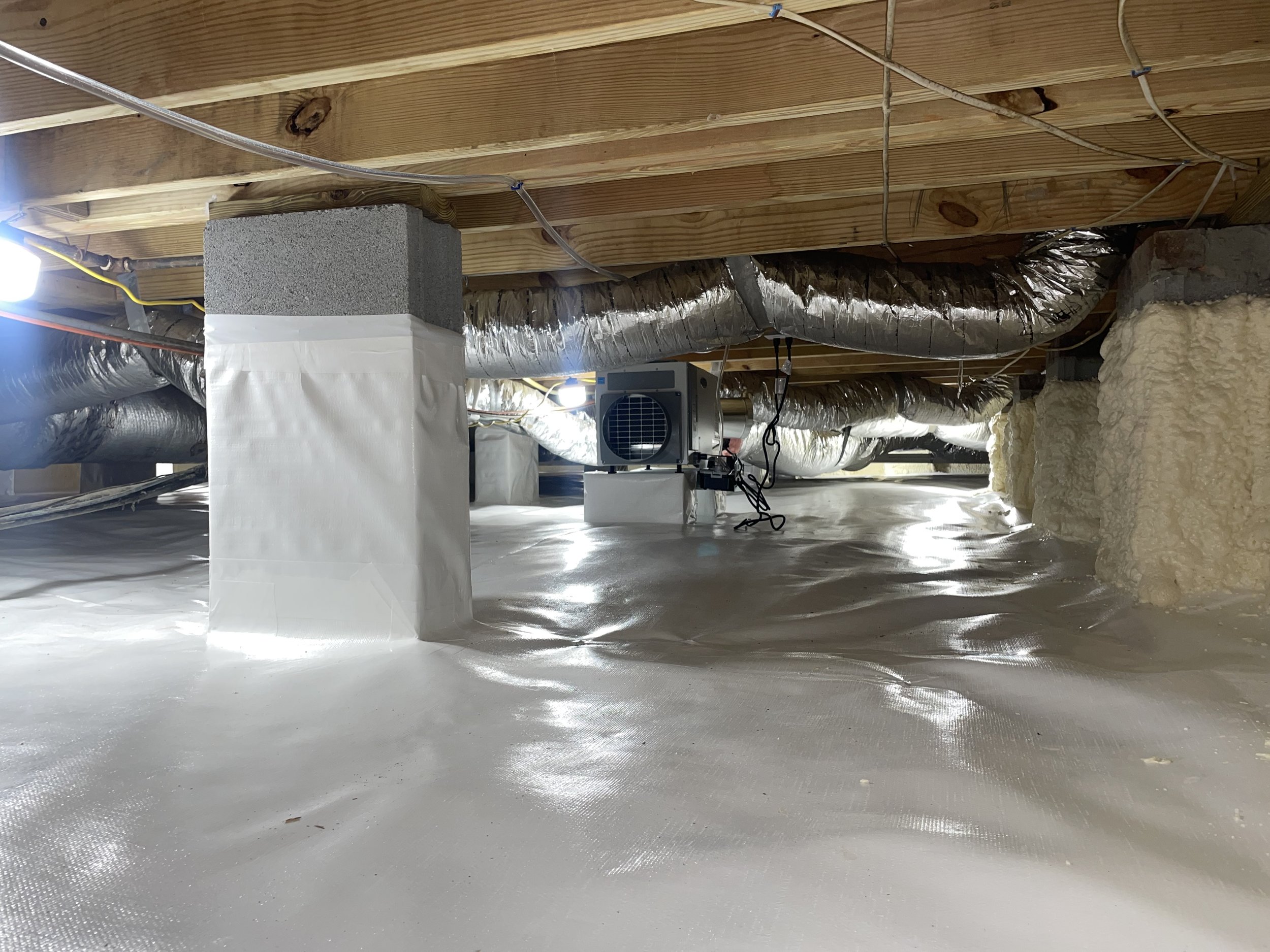 Completed crawl space encapsulation with sealed liner, spray foam insulation, wrapped piers and dehumidifier