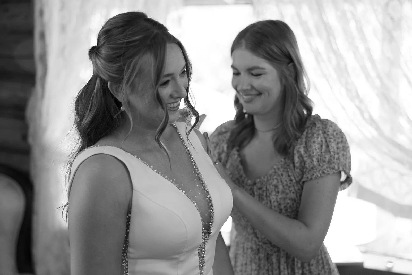 a black and white photo of a makeup artist helping her bride get ready.