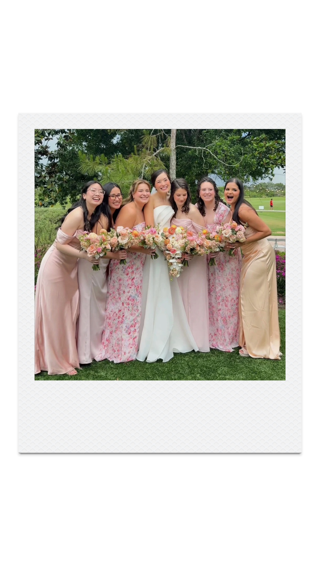 Group of women - bridesmaids and bride, in pastel-colored dresses, holding bouquets, standing outdoors in front of trees and a lawn.