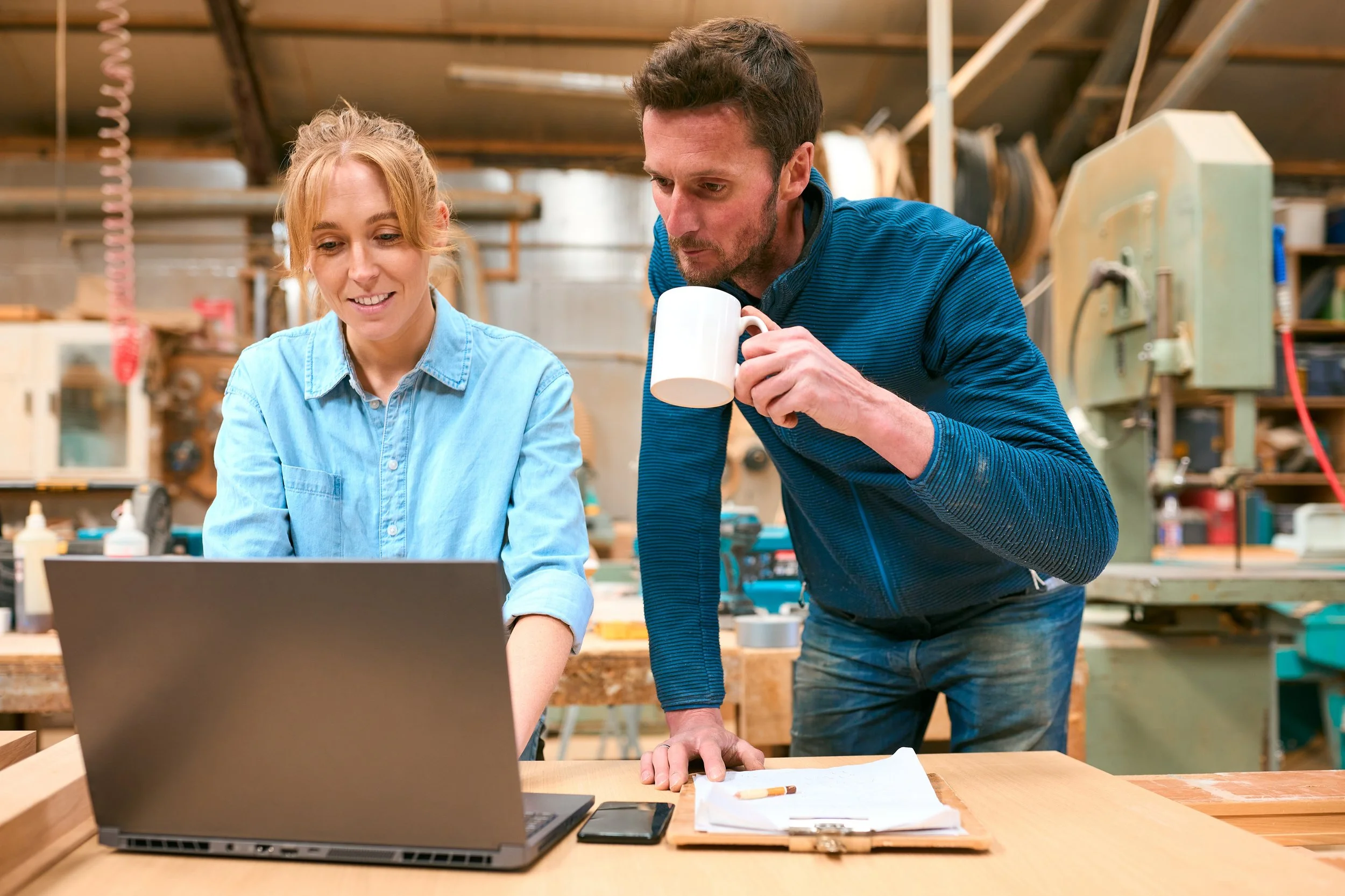 Two small business owners collaborating AI automation and efficiency with a laptop in a production workspace