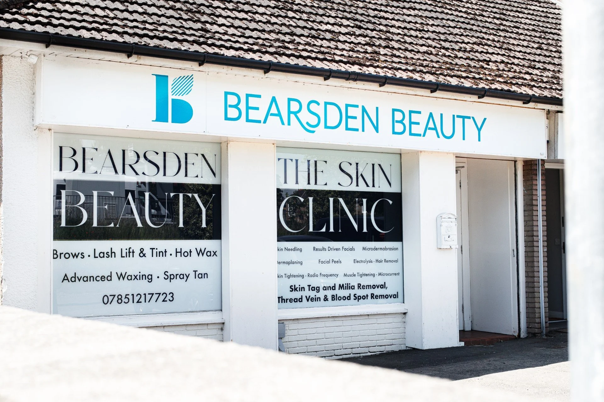 Exterior of a beauty clinic storefront with signage for Beardsen Beauty, listing services like brows, lash lift, tint, hot wax, advanced waxing, spray tan, skin treatment, and hair removal, along with contact information.