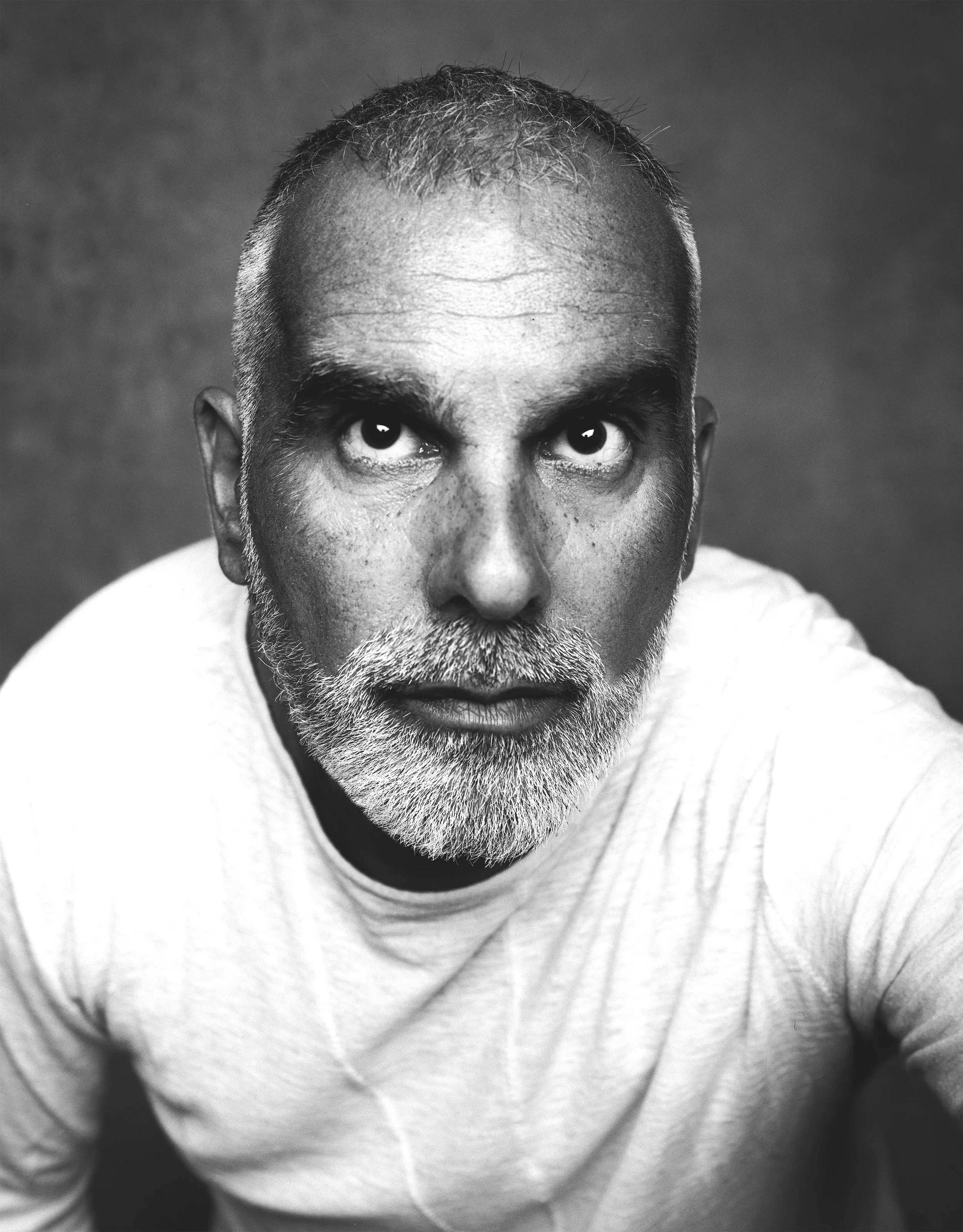 Black and white portrait of a middle-aged man with short hair and a beard, looking directly at the camera.