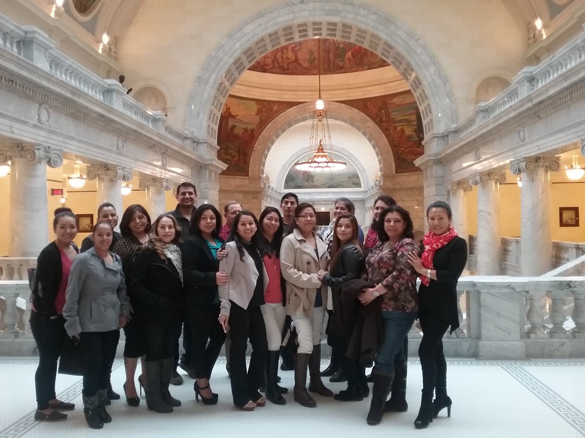 Group of people posing for a photo inside a grand, ornate building with arches, columns, and frescoed ceilings.