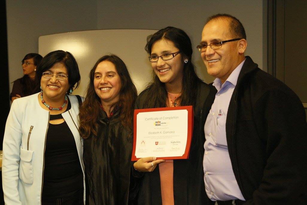 Group of four smiling people at an awards ceremony, holding a certificate of completion.