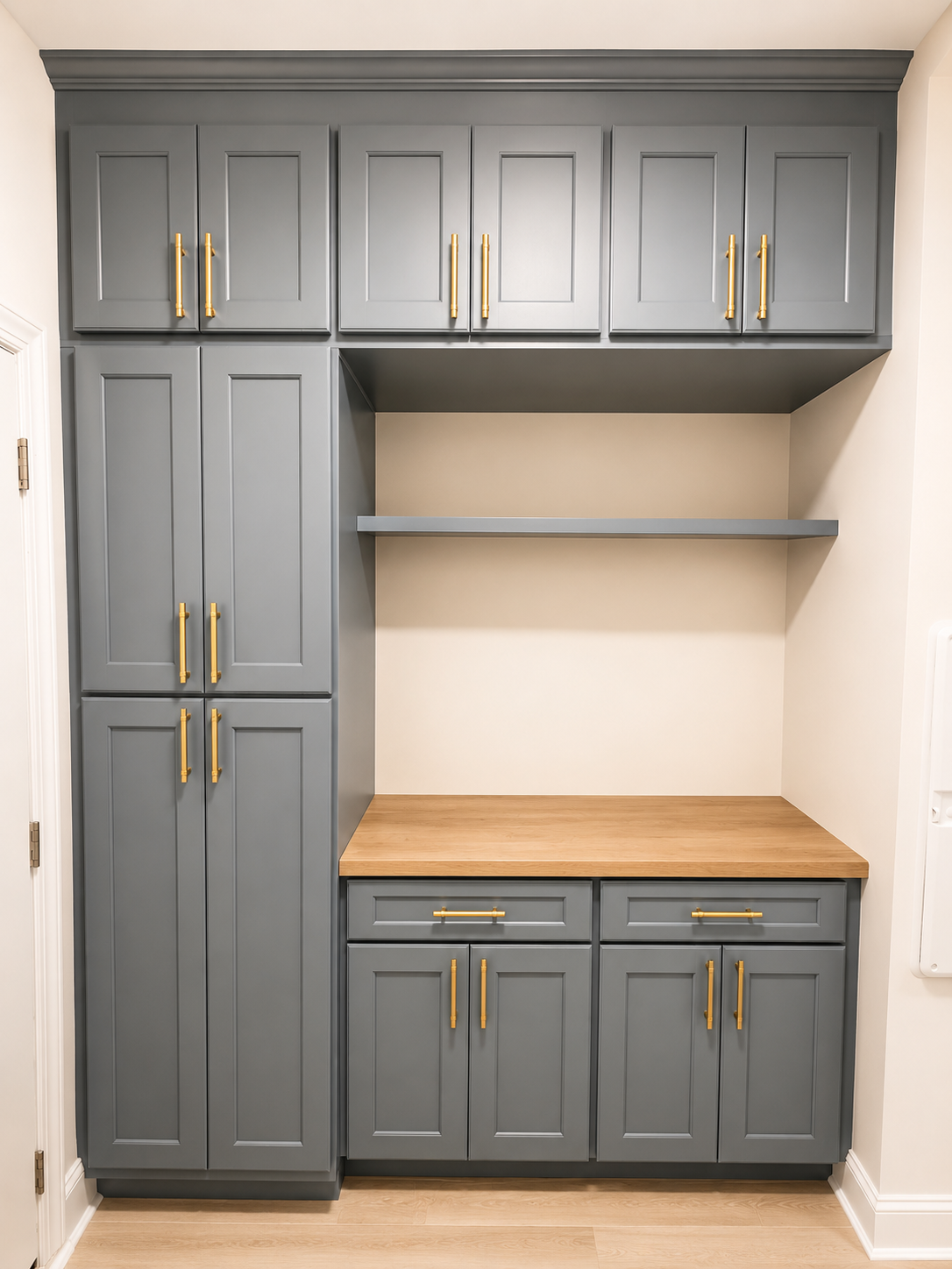 Gray kitchen cabinets with gold handles and a wooden countertop.