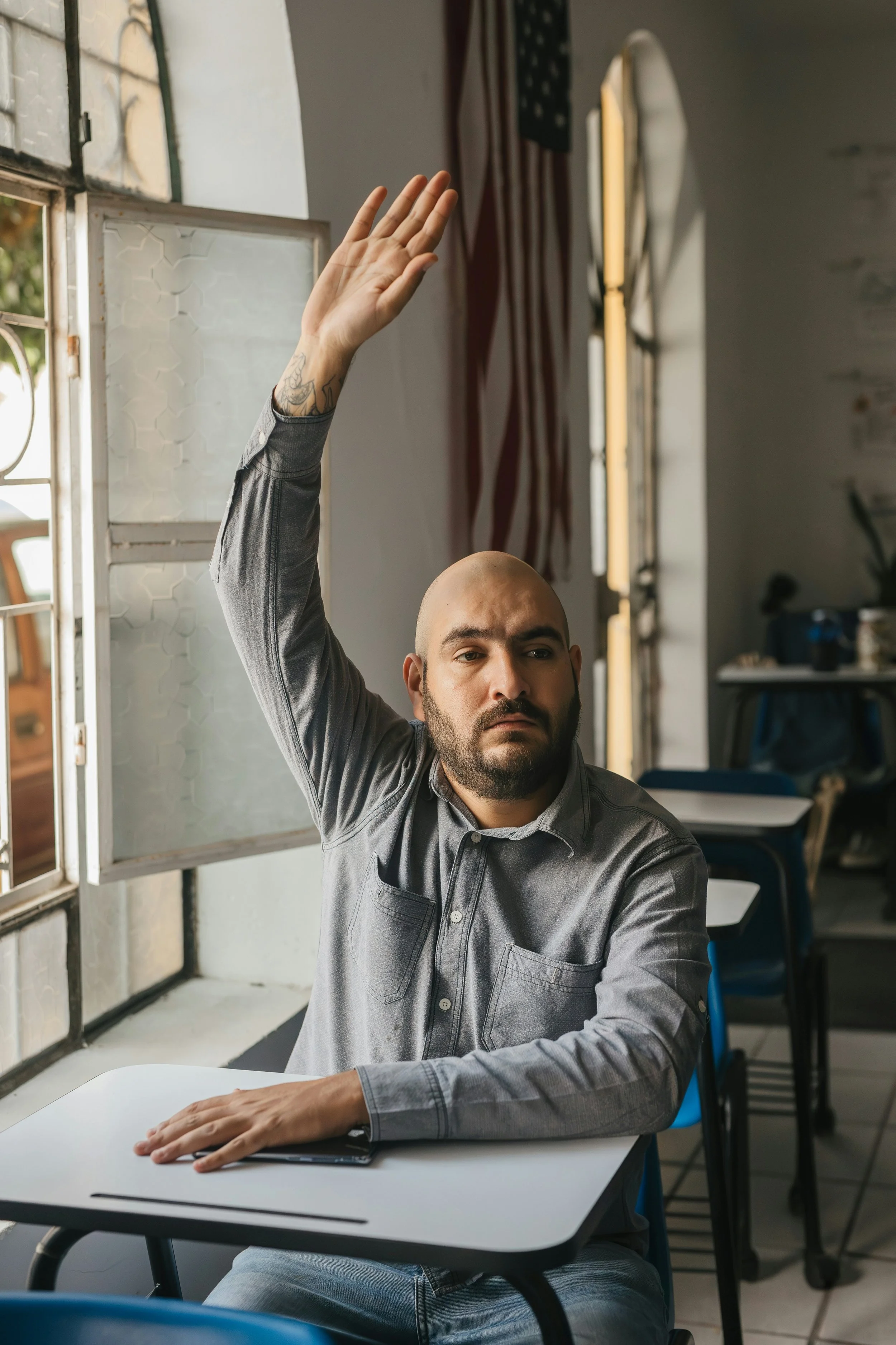 A man with a tattoo on his left wrist raising his right hand. He has questions about nurse advocates, patient advocates, and how Call My Nurse Advocate, PLLC helps clients.