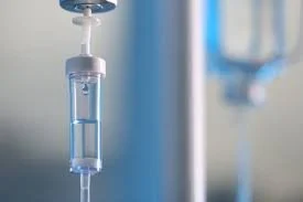 Close-up of a medical intravenous (IV) drip hanging from an IV pole.