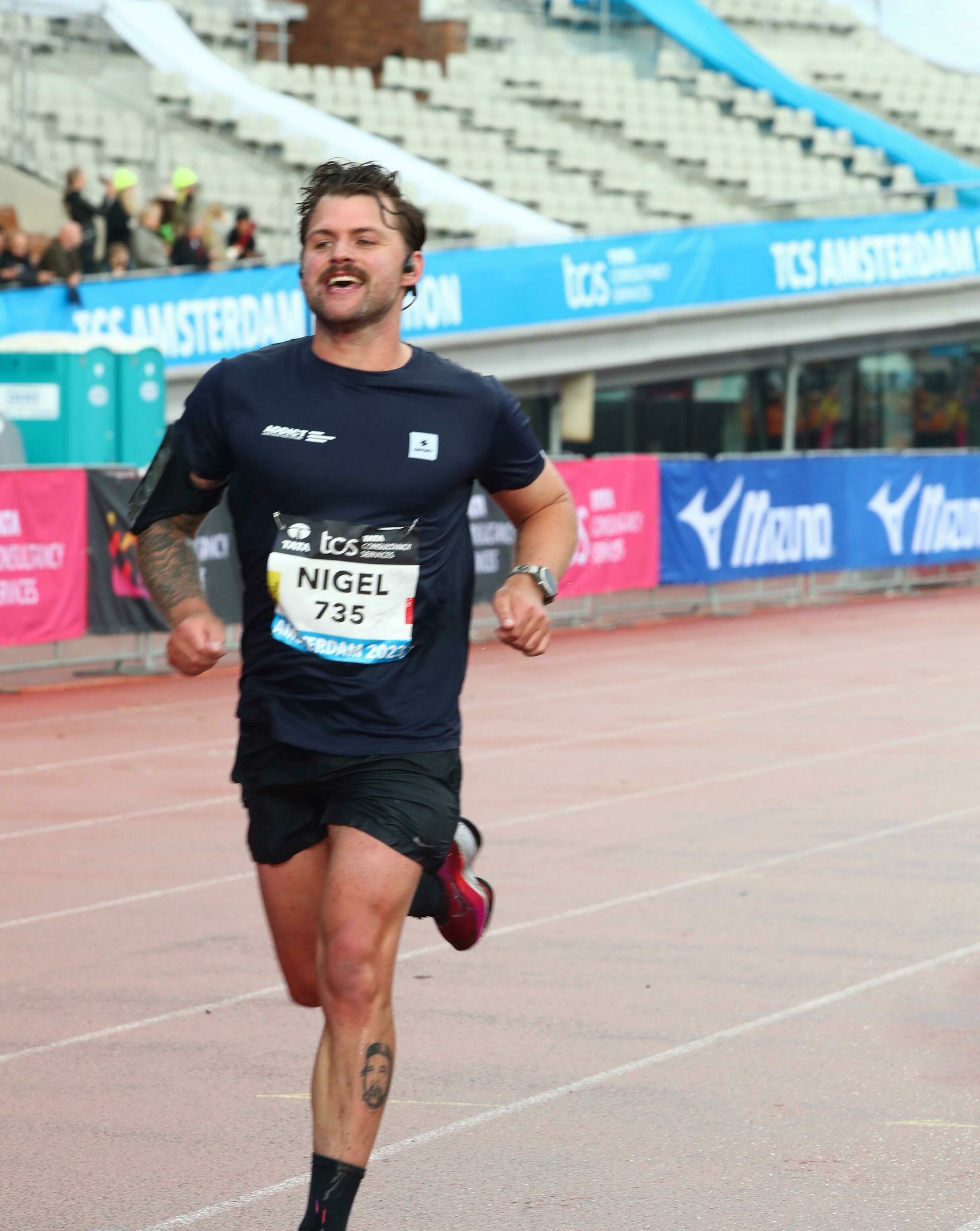 Een man met een wedstrijdnummer 735, die loopt op een atletiekbaan tijdens een marathon in Amsterdam.