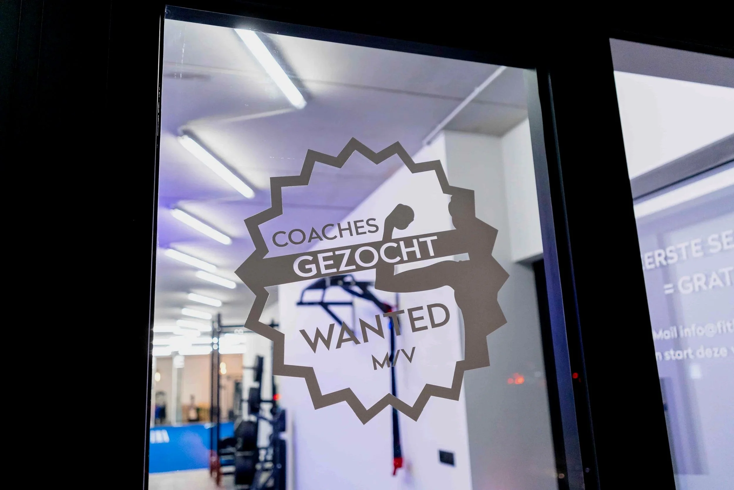 Raam met een poster die vraagt om coaches, met woorden zoals 'GEZOCHT', 'WANTED', en andere tekst die niet volledig leesbaar is.