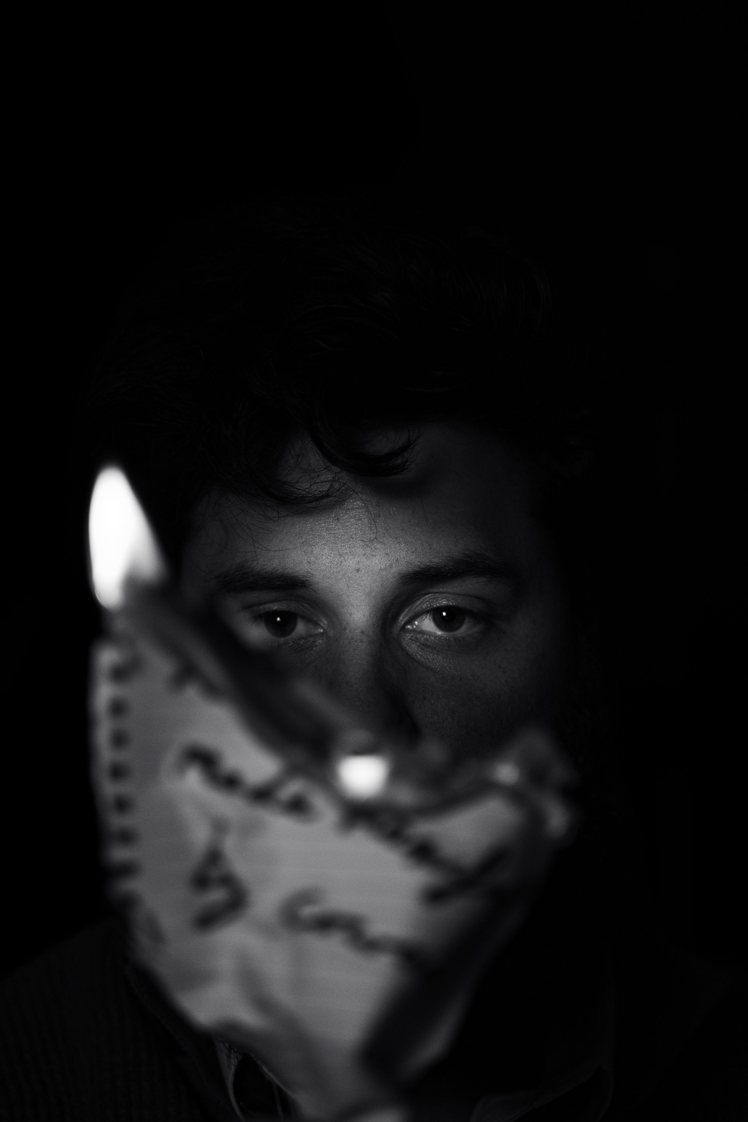 Close-up of a person's face partially covered by a patterned cloth, with focus on their eyes and forehead.
