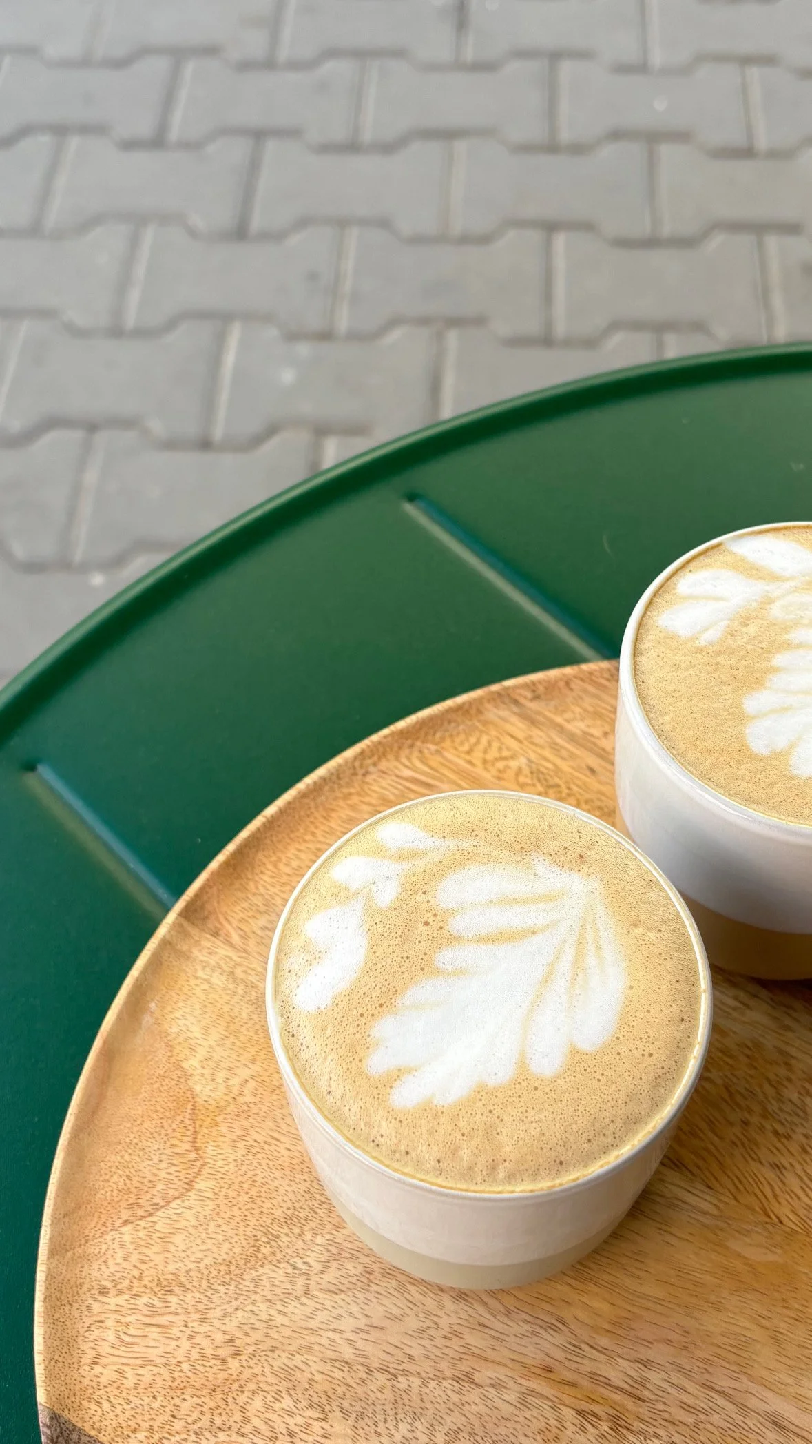 Two lattes on a green table