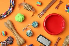 Dog toys including a rope toy, a green ball, a blue ball with white stripes, a bone, a small red dish, a dog collar, and a smartphone on an orange background.