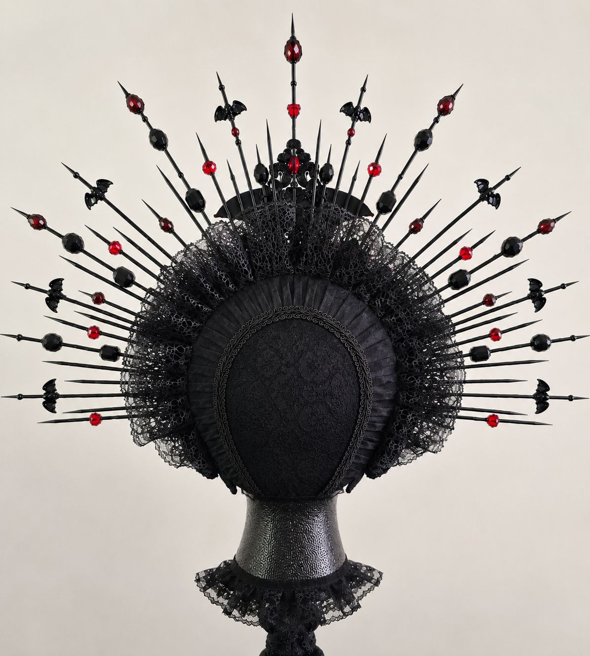 An elaborately decorated black headpiece with lace, spikes, and red and black ornaments, resembling a crown or headdress.