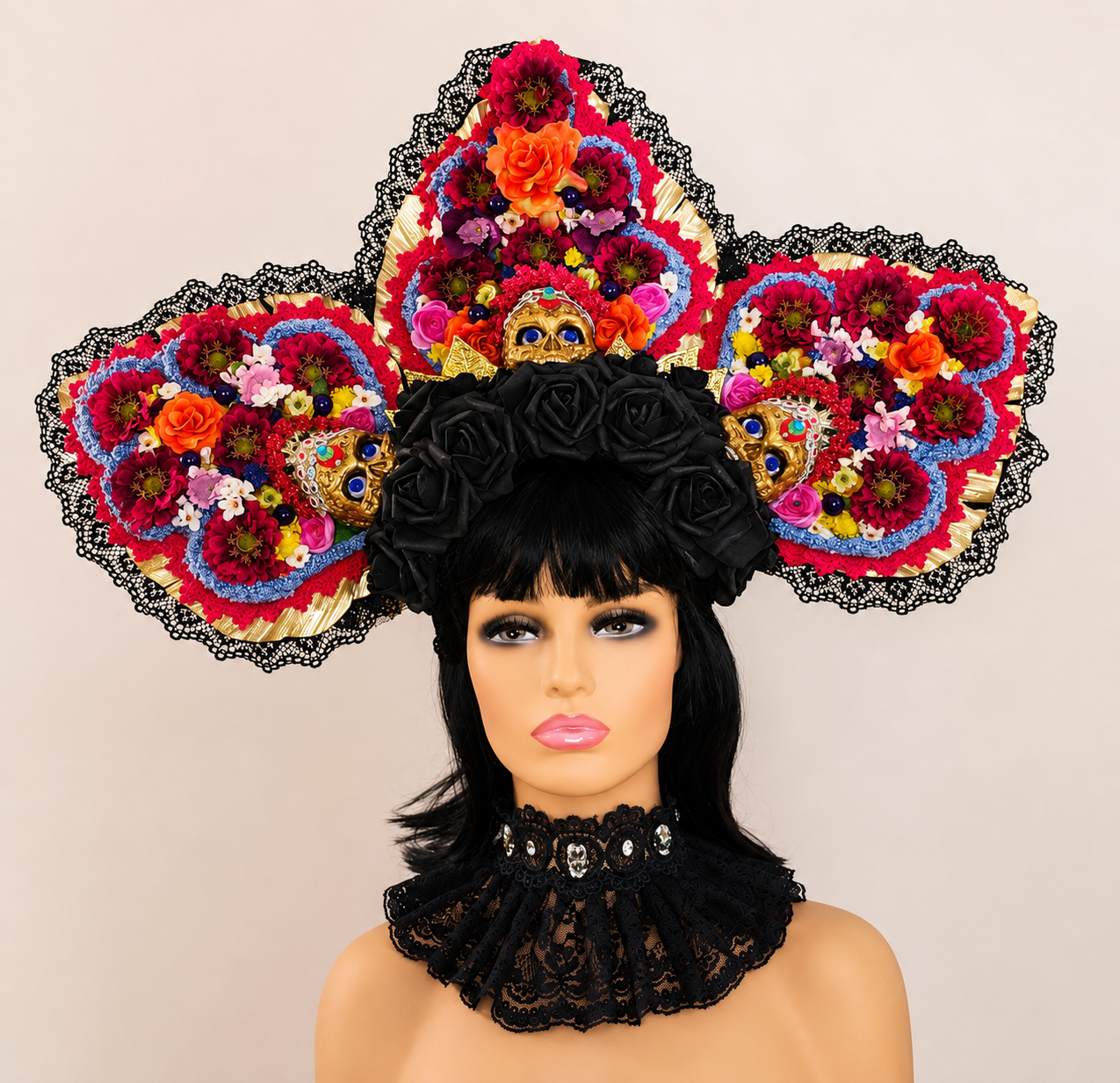 Mannequin with black hair wearing a black lace choker and an ornate, large floral headdress featuring colorful flowers, skull motifs, and black lace accents.