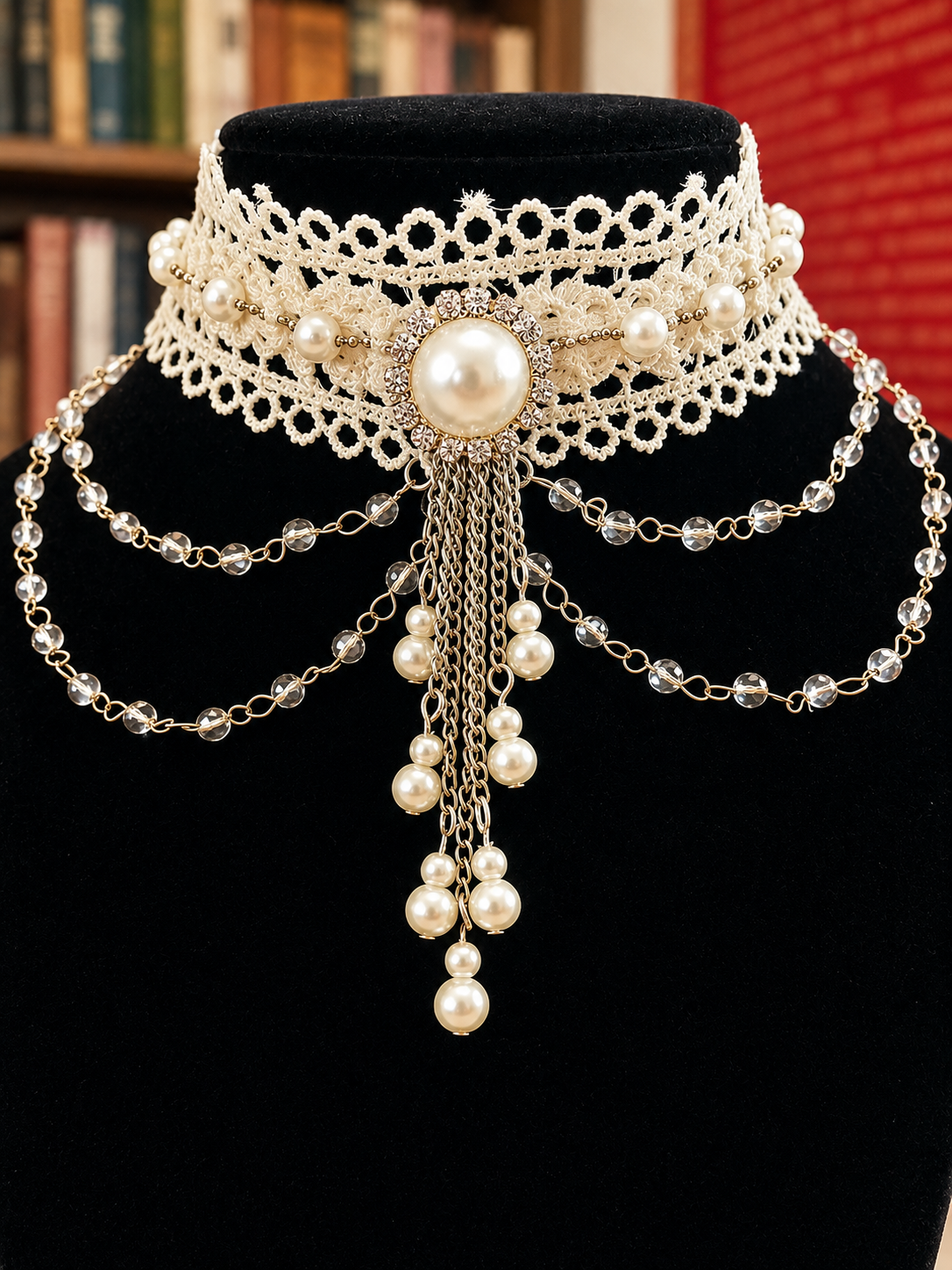 A choker necklace with large pearl centerpiece and dangling chains, layered with pearl and crystal beaded chains, displayed on a black velvet bust.