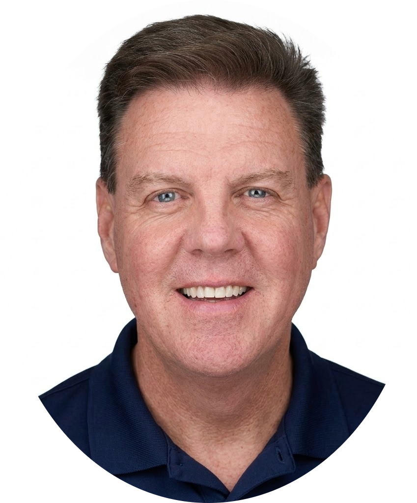 Smiling middle-aged man with short brown hair and blue eyes, wearing a dark collared shirt, against a white background.