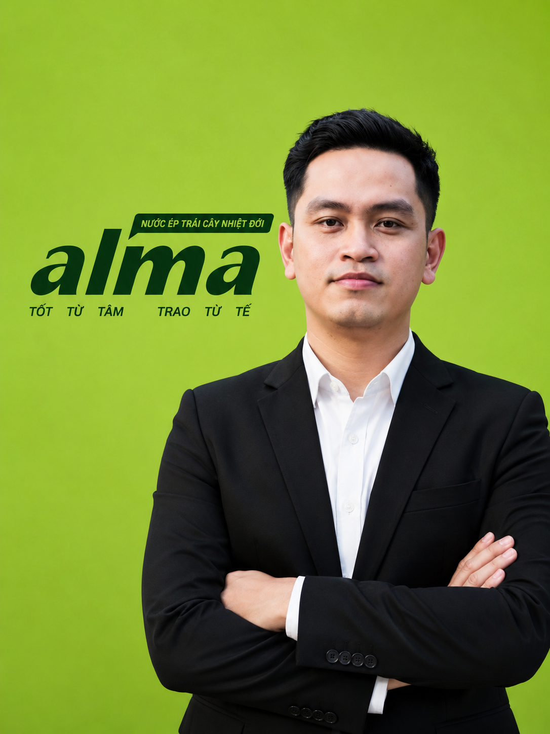 A young man in a black suit with a white shirt, standing with arms crossed in front of a green background with Vietnamese text promoting a product called 'alma' and emphasizing natural and quality ingredients.