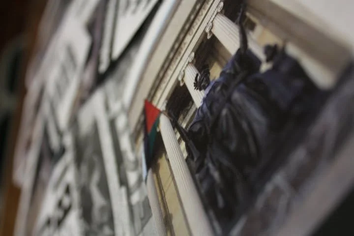 A store shelf stocked with various packages, including black plastic bags. There is a small colorful triangular flag hanging in front of the packages.