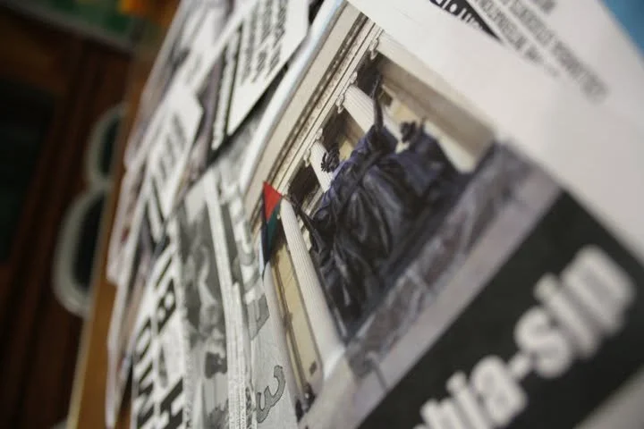 A newspaper with a photo of hanging black jackets on a rack. The image is angled and slightly blurred.