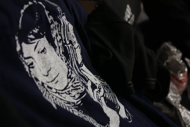 Close-up of a dark blue hoodie featuring a white line art illustration of a person's face with long hair on the front.