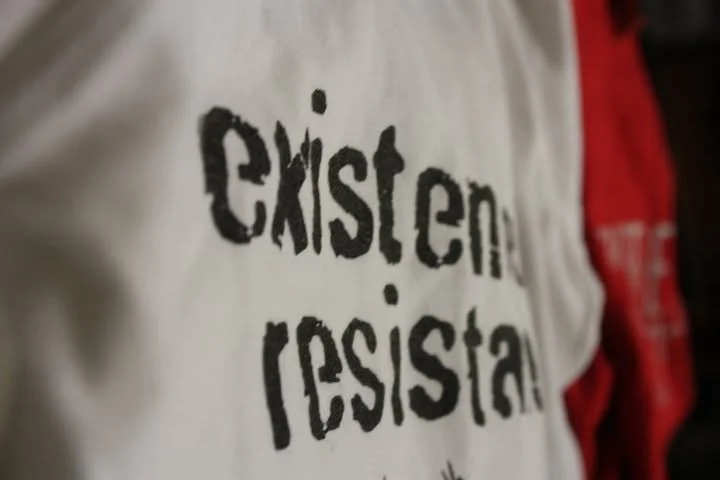 Close-up of a white and red shirt with the text 'Christian Residual' printed in black.