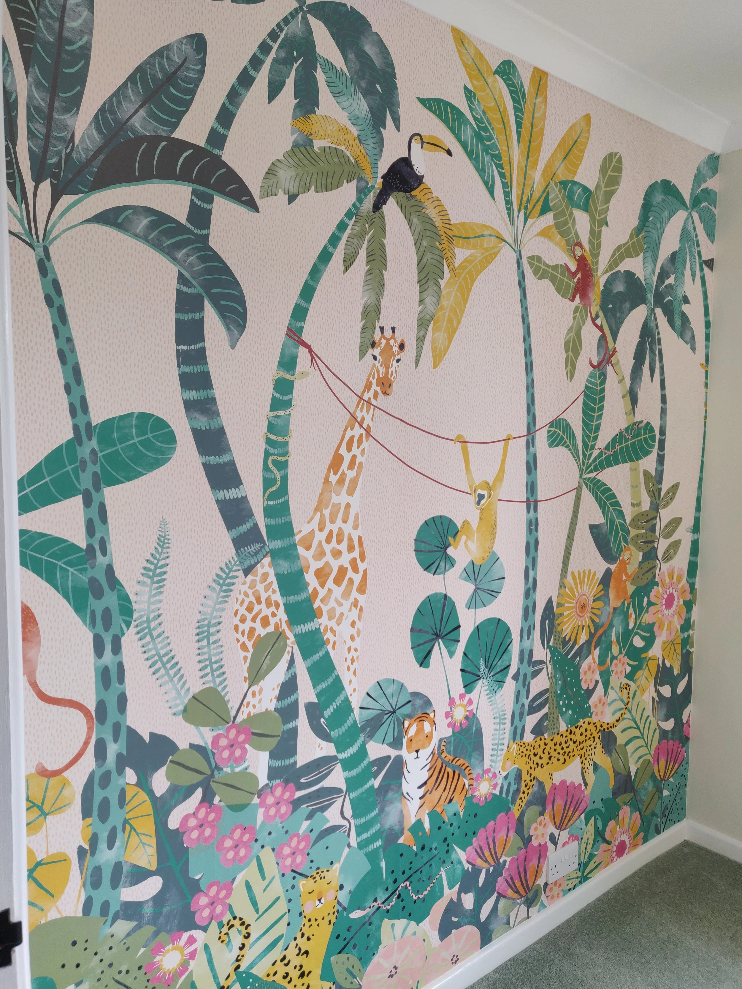 Colorful jungle scene mural with tall green and blue palm trees, pink and yellow flowers, a giraffe, a cheetah, a monkey, and a tiger, set against a pink dotted background.