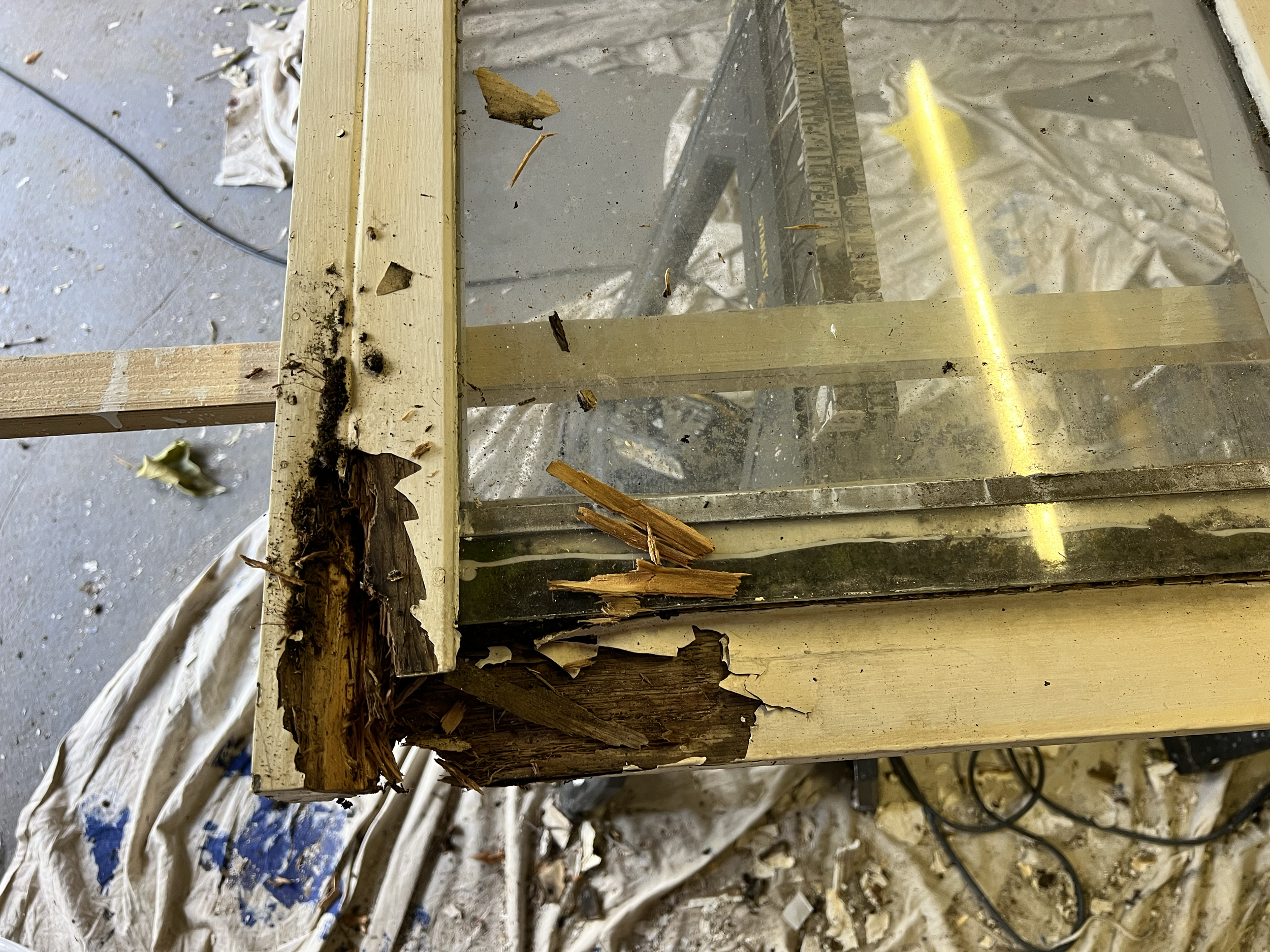 Damaged wooden frame with broken wood and debris scattered around, construction or renovation site.