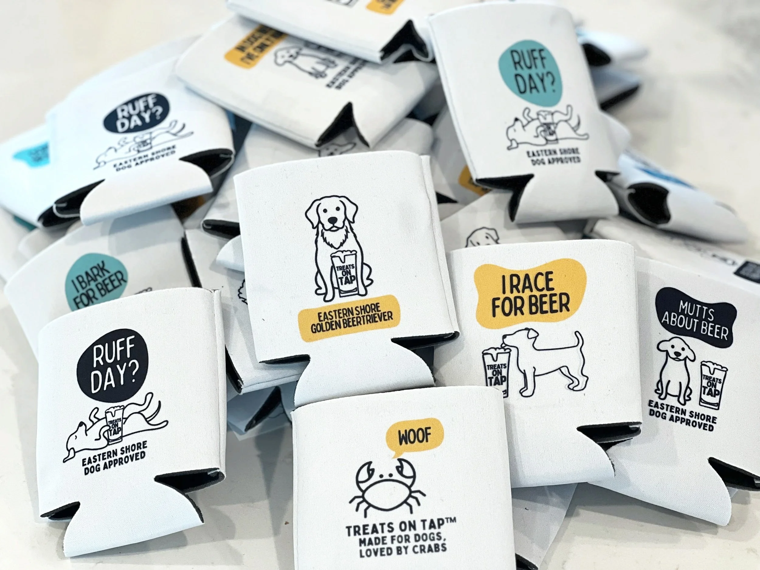 A pile of small white paper wrappers with various black and colored illustrations and texts related to dogs and beer, including phrases like 'Ruff Day?', 'Treats on Tap', and 'Woof', with cartoon dog and beer mug designs.