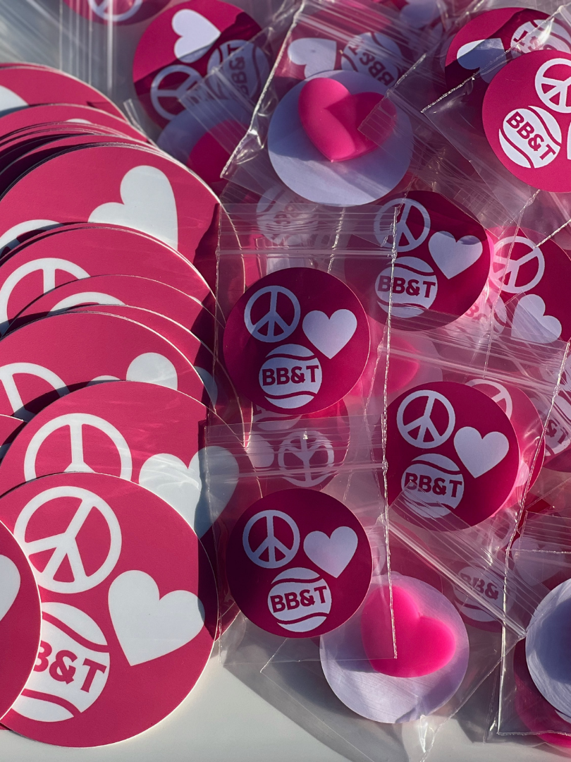 Multiple pink stickers and small heart-shaped objects with peace symbols, hearts, and the text 'BB&T' on them, some in clear plastic bags.