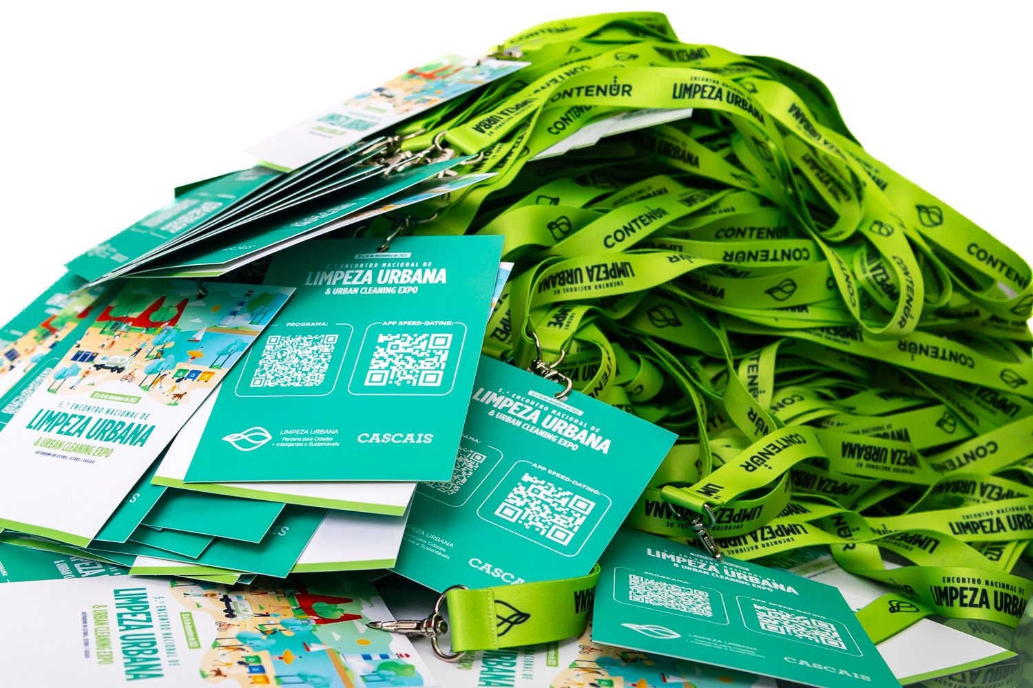 Abadás de brindes, pulseiras verdes de toque macio com escrita em preto, cartões de evento em cores verdes e desenhos de personagens, logo do evento 'Encontro Nacional de Limpeza Urbana' com a palavra 'Cascais' ao fundo, e o destaque para o tema 'Limpeza Urbana'.