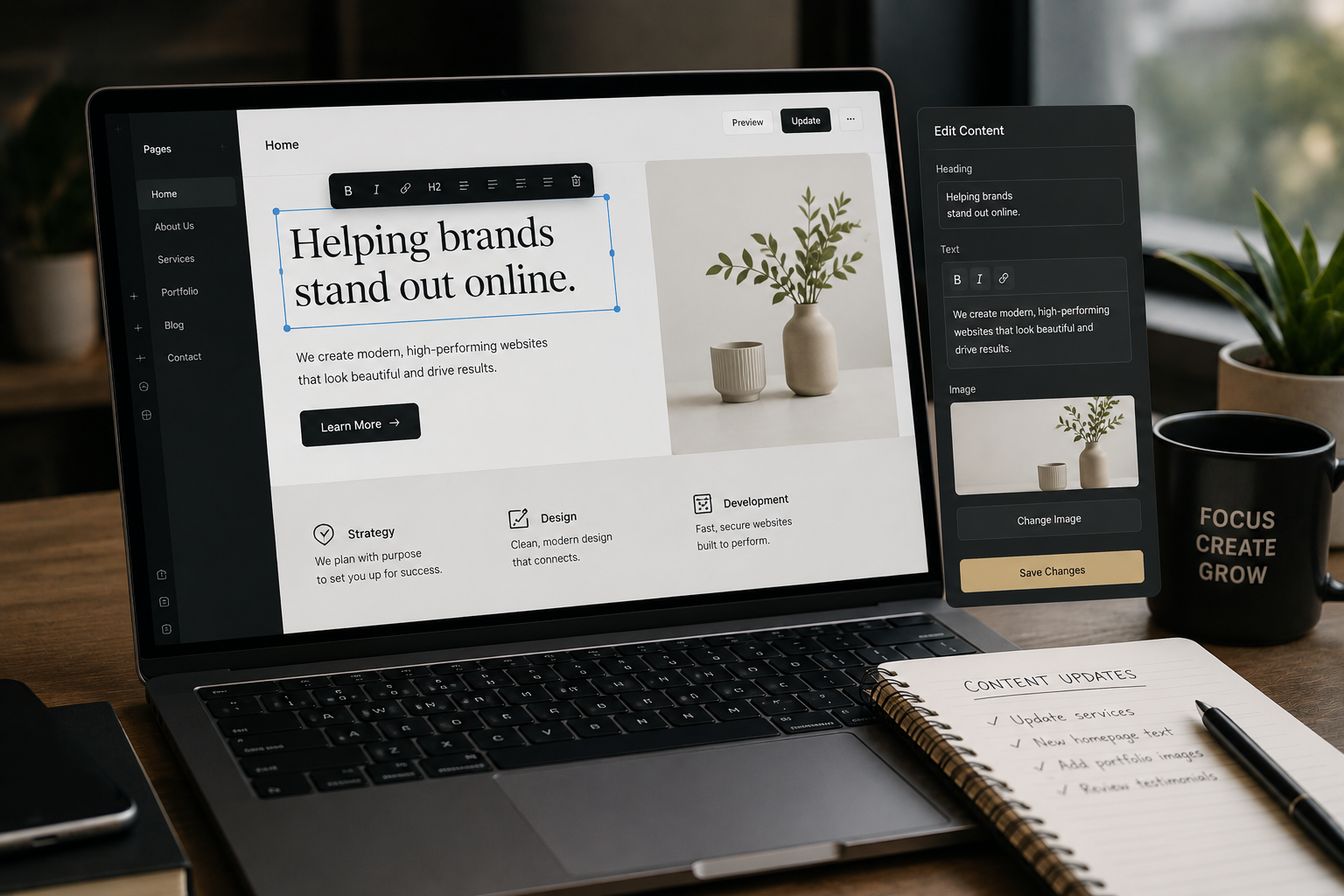 A laptop on a desk displaying a website editing interface for a business helping brands stand out online, with a notebook and pen nearby and a mug with motivational text.