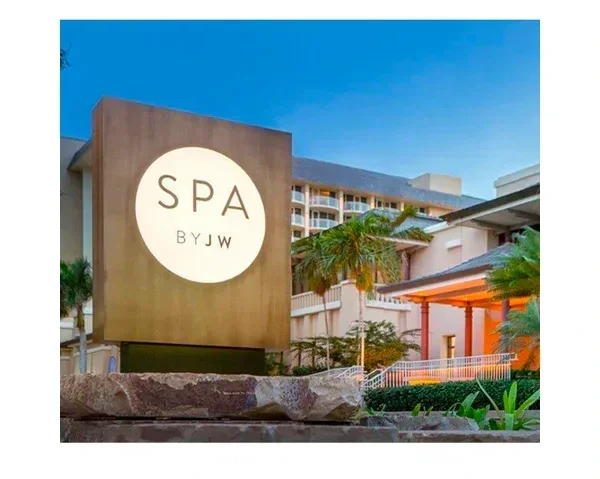 Spa by JW hotel with palm trees and modern building in the background under a clear blue sky.