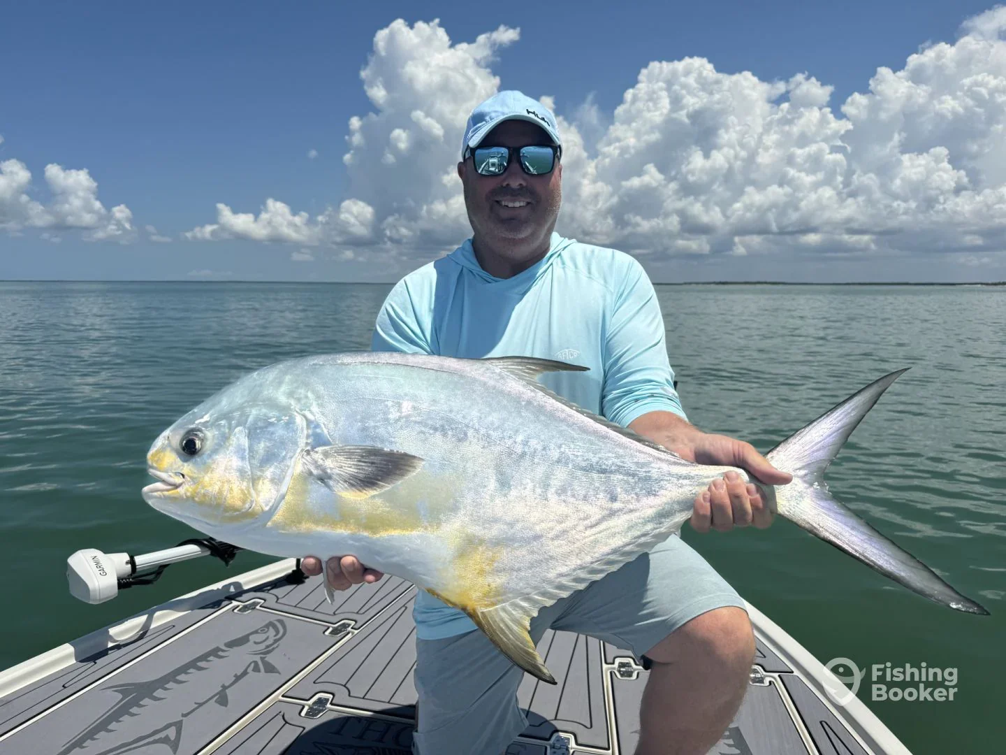 Man on boat holding a large fish in a body of water.