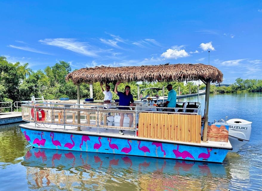 People enjoying a boat ride on a canal with lush green trees, under a clear blue sky.