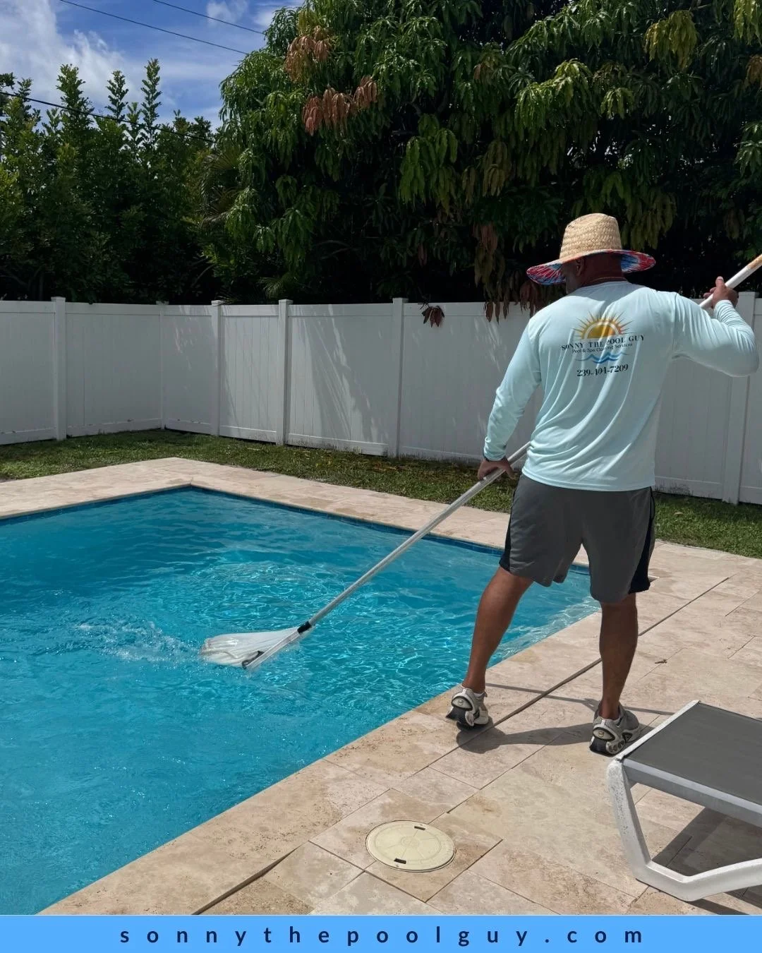A man wearing a sun hat, long-sleeve shirt, and shorts cleaning a swimming pool with a pool skimmer pole.