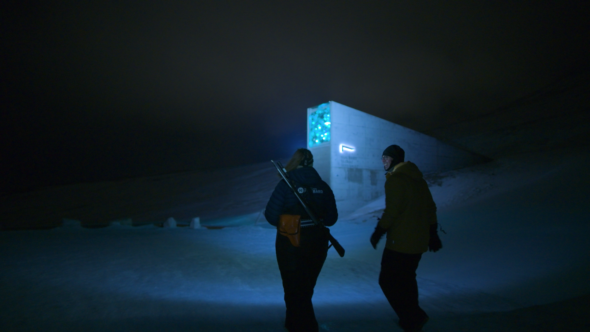 Dr. K. Aleks Schaefer walks with a local tour guide towards the Svalbard Global Seed Vault during polar winter