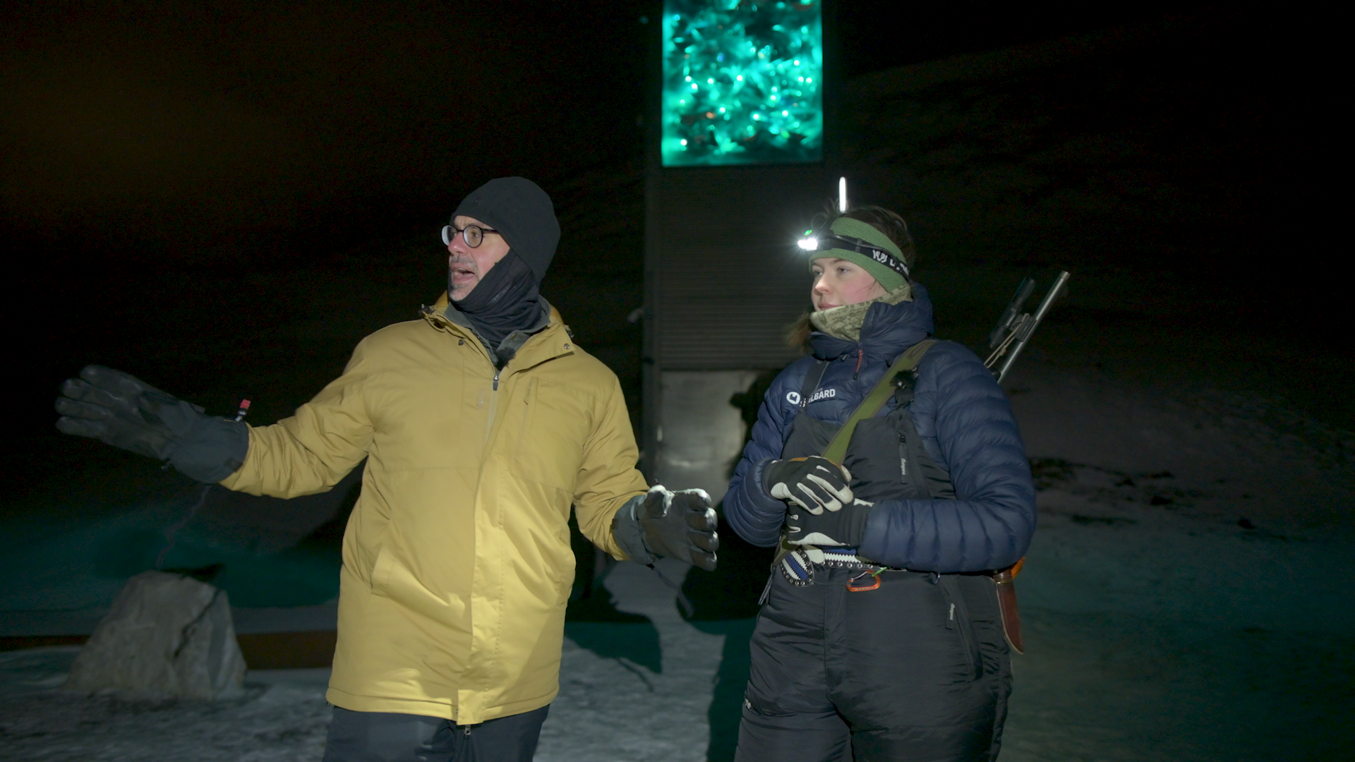 Dr. K. Aleks Schaefer and a local tour guide stand outside the Svalbard Global Seed Vault during polar night with snow on the ground