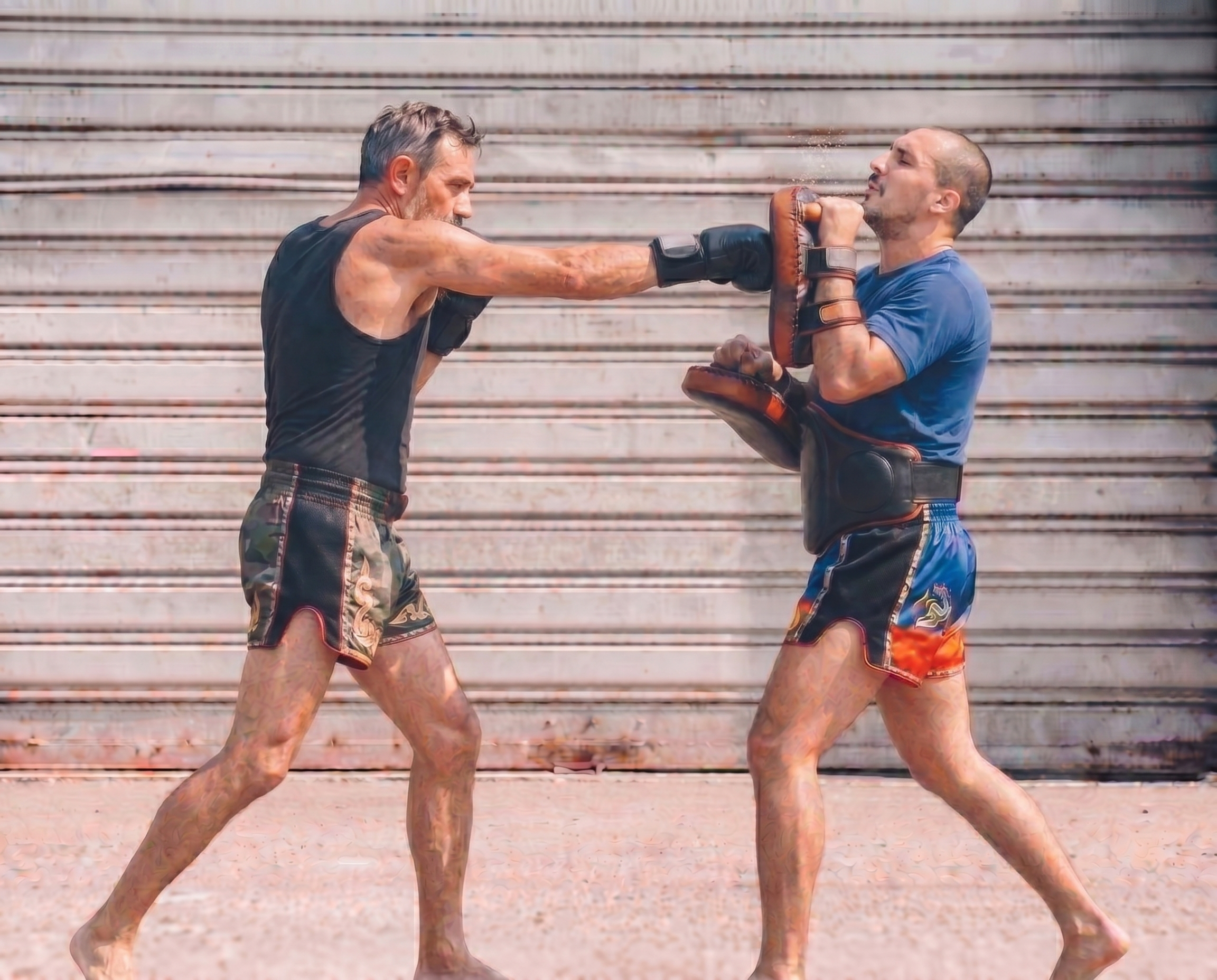 Zwei Männer trainieren im Boxen auf der Straße, einer schlägt den anderen, der Boxhandschuhe trägt, in einen sparring-Stand.