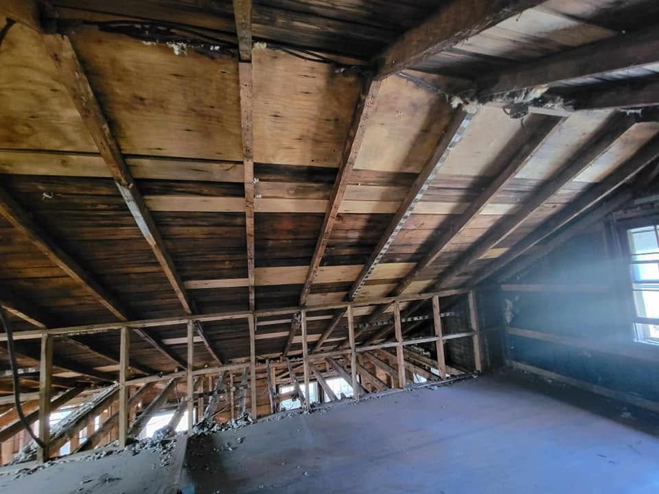 Empty attic with exposed wooden beams and roof framing.