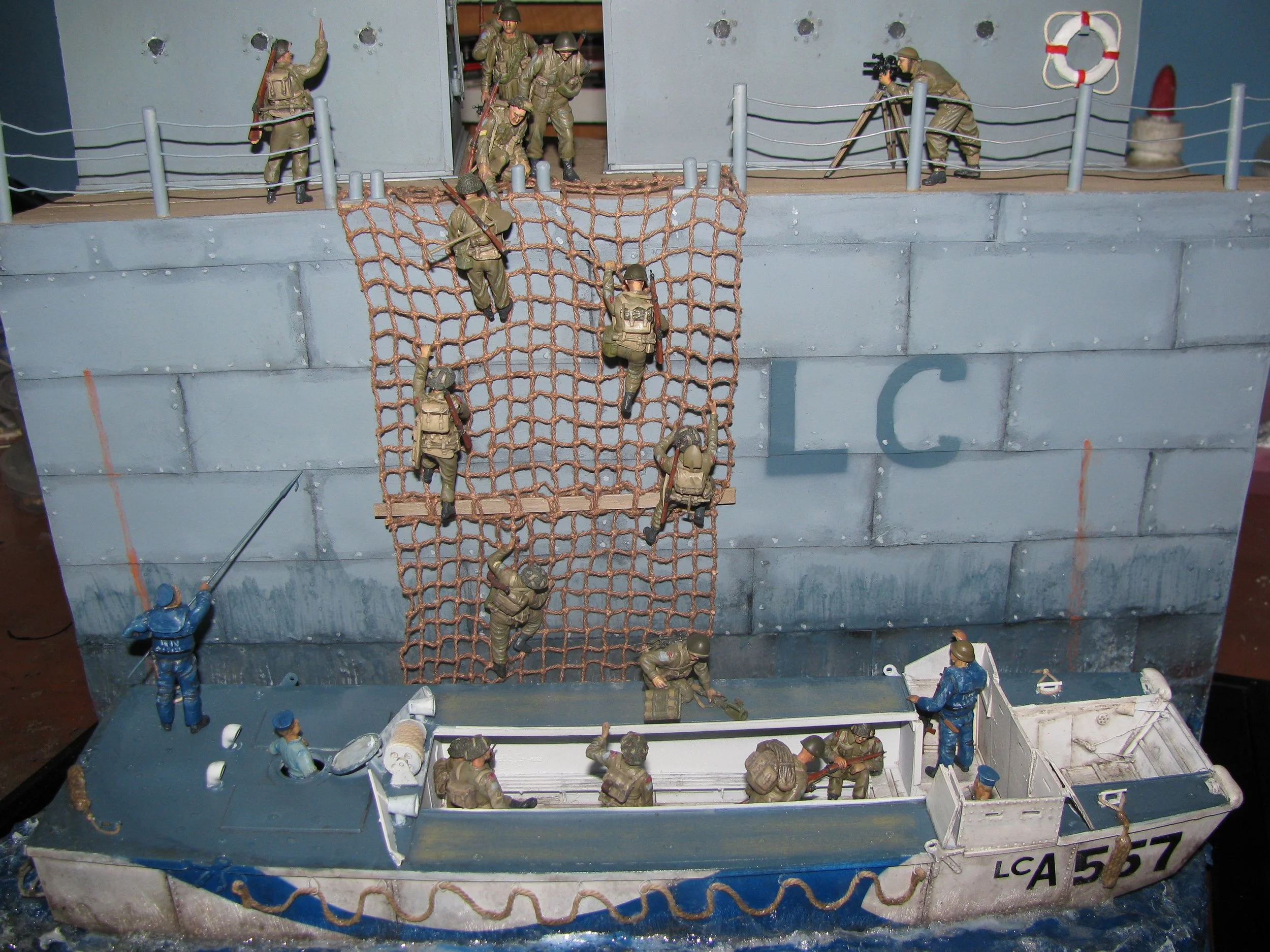Miniature military scene with soldiers on a DUKW climbing up the scrambled net on the side of a ship.