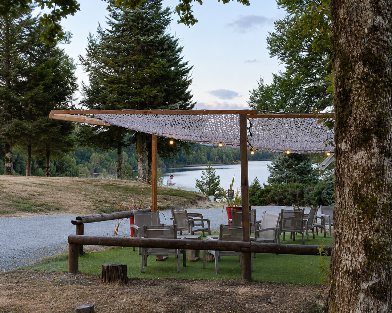 Outdoor patio area with chairs and a canopy, overlooking a lake with trees in the background.