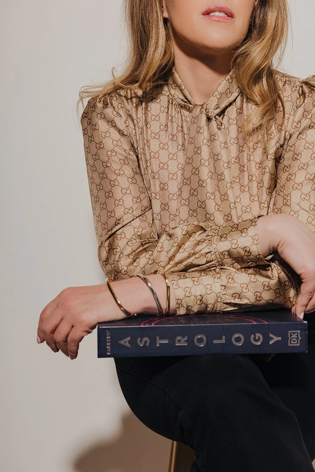 A woman wearing a Gucci patterned blouse holding a book titled 'A Stark Lawy'.