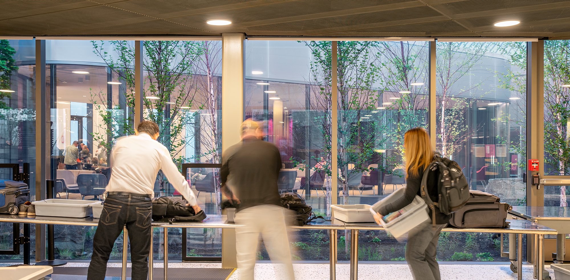 People at an airport baggage claim area, retrieving bags from a conveyor belt.