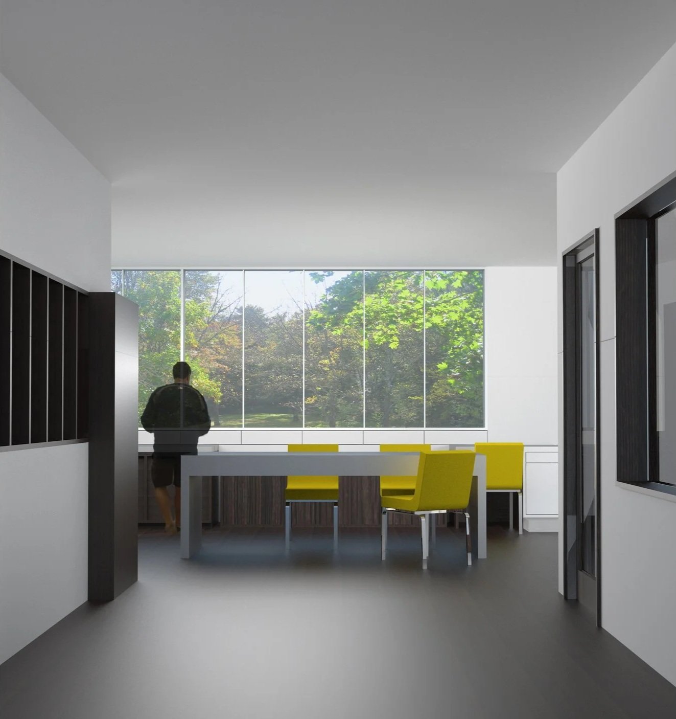 Interior of a modern building with large windows showing green trees outside, a person standing near the window, and yellow chairs around a white table.