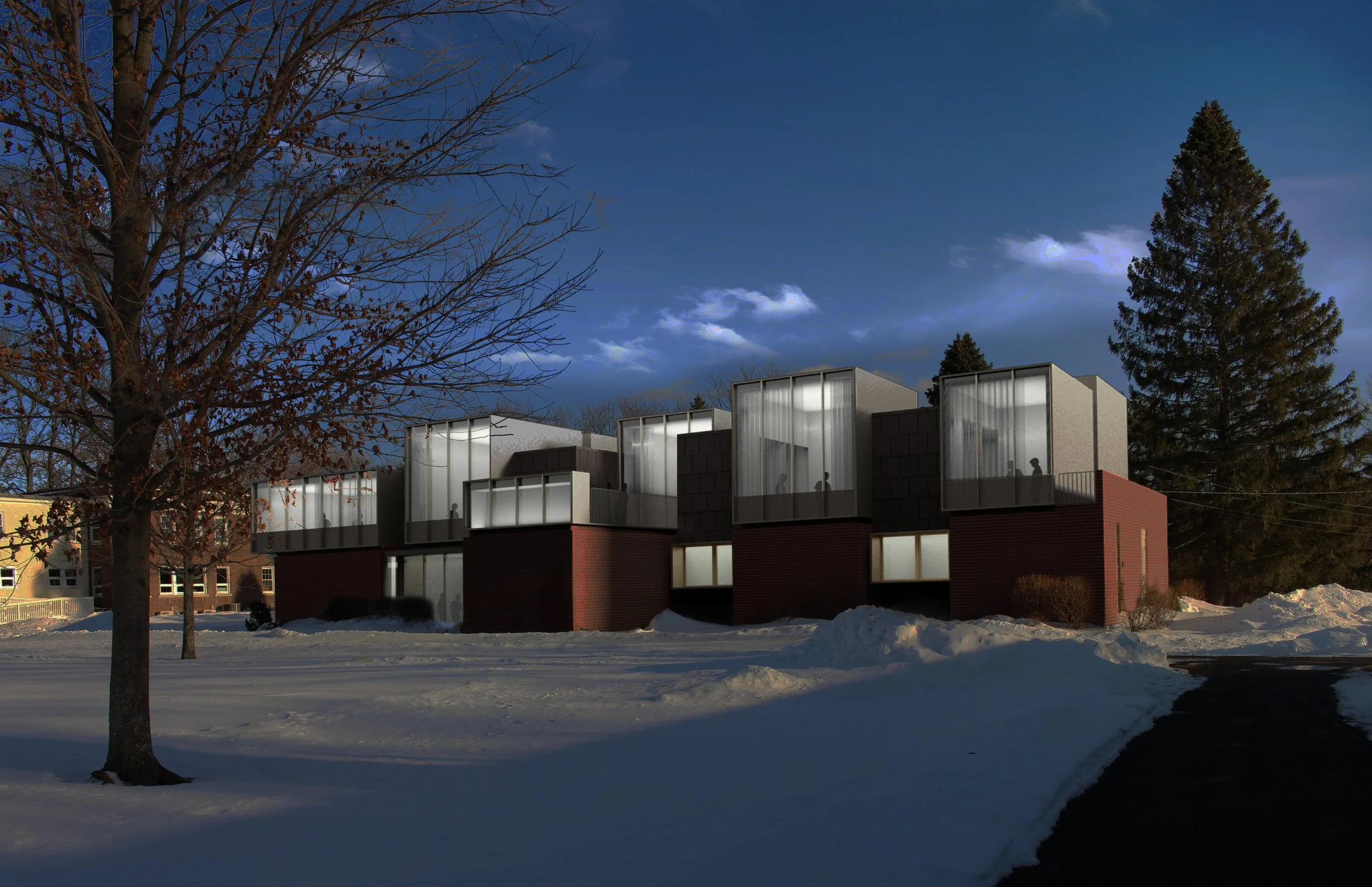 Modern residential buildings with large glass windows on a snowy landscape, under a clear blue sky with some clouds. There are tall trees around the buildings, some bare and others evergreen.